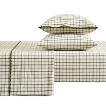 A neatly made bed with two stacked pillows and a sheet set featuring a cream background and green checkered pattern, with a decorative green stitched border on the pillowcases and sheets.