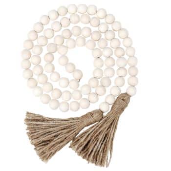 A string of round, white wooden beads arranged in a spiral, ending with two brown jute tassels—perfect wall crafts for fall décor.