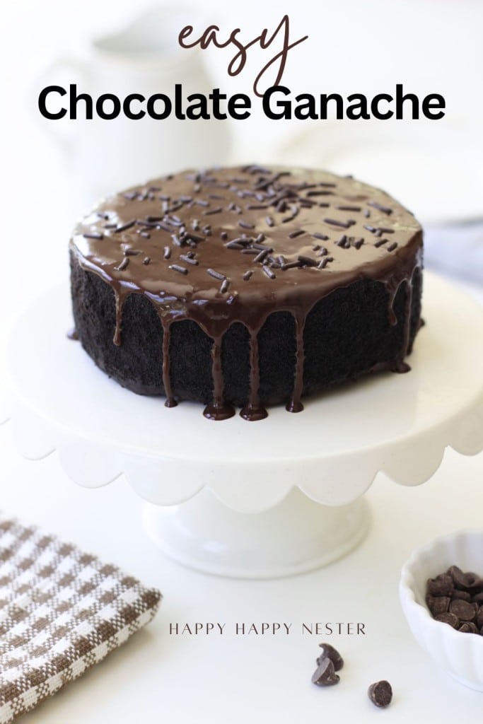 A round chocolate cake topped with glossy chocolate ganache and chocolate sprinkles sits on a white cake stand. The text reads "easy chocolate ganache recipe." A napkin and chocolate chips are nearby.