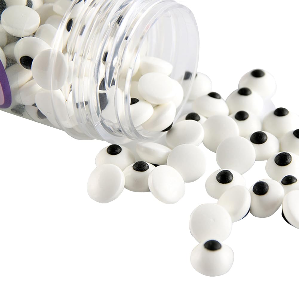 A plastic container tipped over, spilling small white candy eyes with black centers onto a white surface—perfect for decorating your favorite Halloween bark recipe.