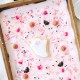 A rectangular sheet cake with pink frosting is decorated with Halloween-themed sprinkles, candy eyes, and a central ghost-shaped cookie—perfect for pairing with your favorite Halloween bark recipe (easy). The cake sits in a metal pan on a festive table.