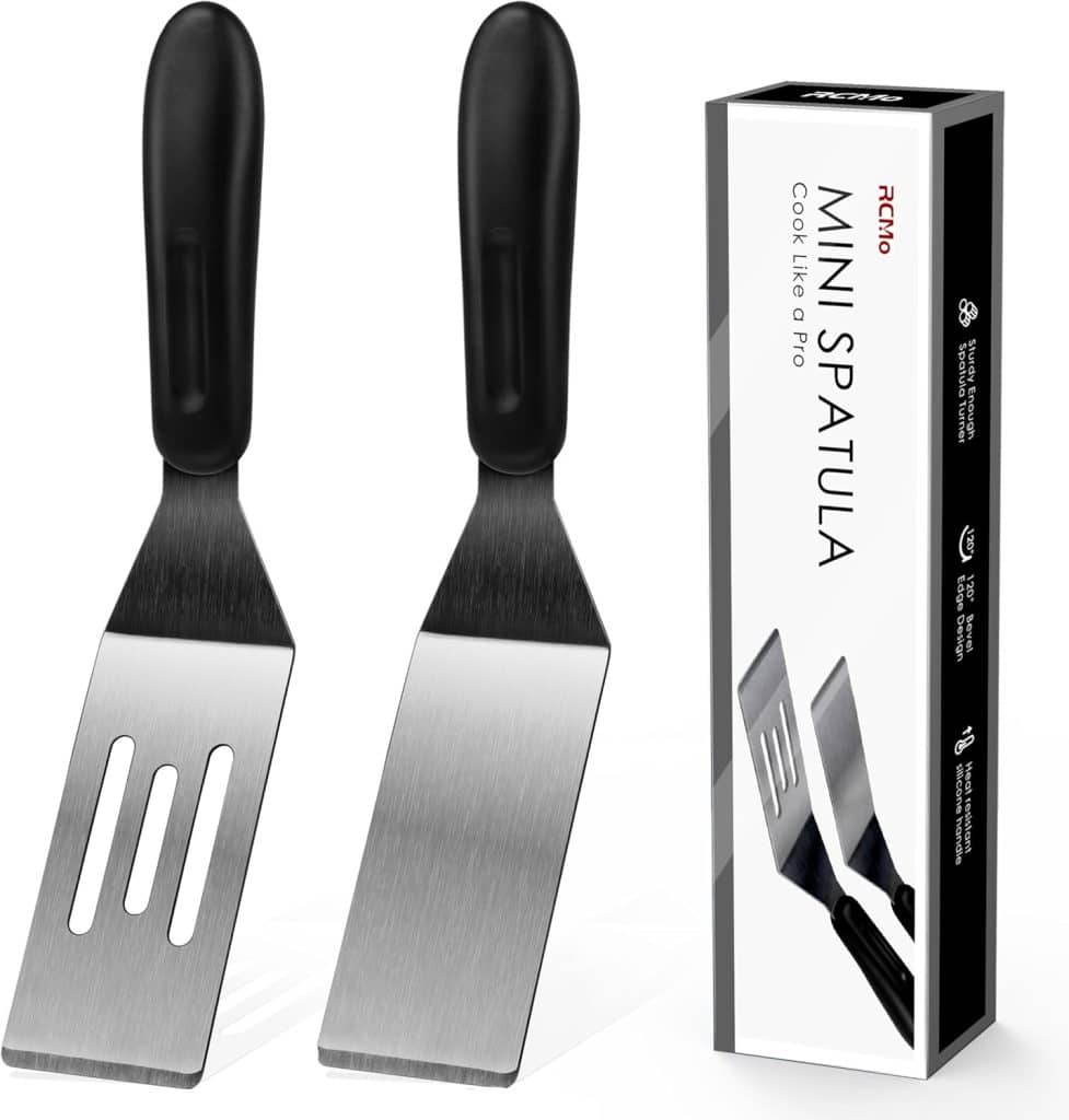 Two stainless steel mini spatulas with black handles, ideal for serving treats like pumpkin bread pudding recipe, are shown next to their product box labeled "Mini Spatula." The box features images of the spatulas and product details.