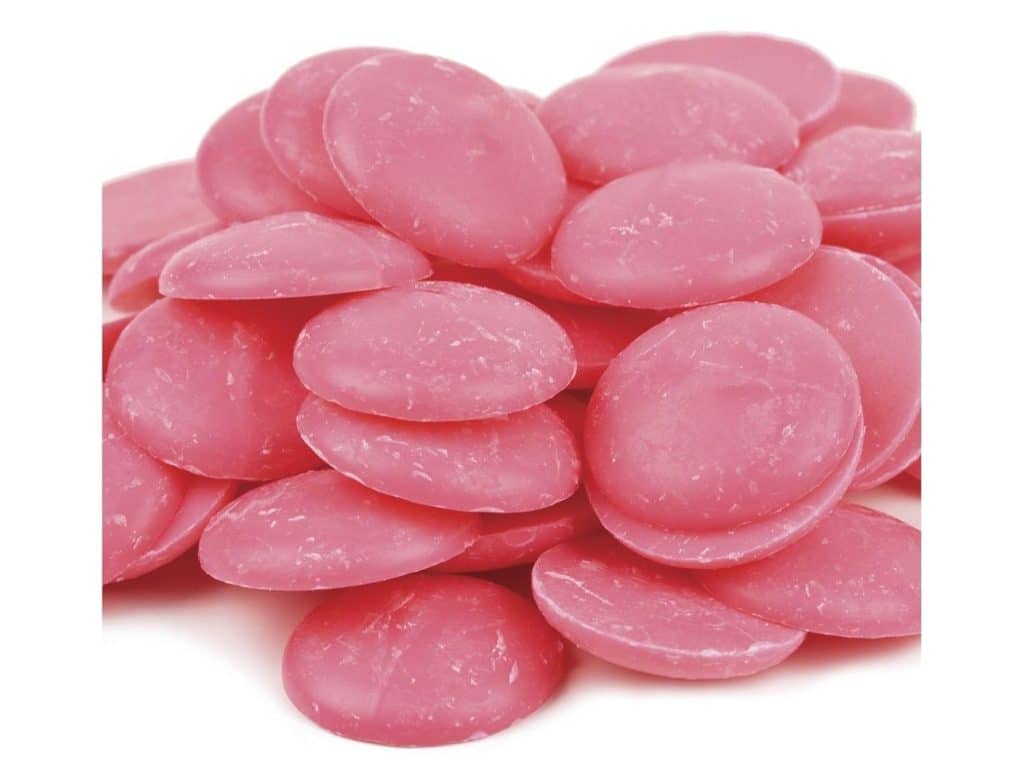A pile of round, flat, pink candy melts with a slightly chalky texture, stacked on a white background—perfect for adding to your next Halloween bark recipe.