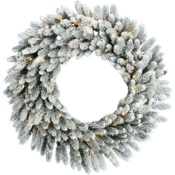 A frosted artificial pine wreath decorated with small, warm white lights, arranged in a circular pattern against a white background.