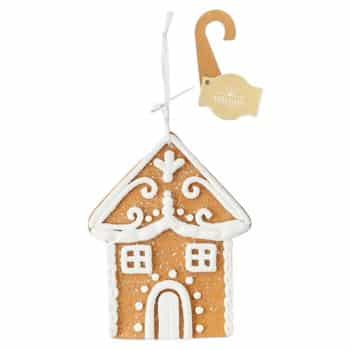 A gingerbread house ornament decorated with white icing details, featuring windows, a door, and a swirl roof pattern. It hangs from a white string and has a brown tag attached.