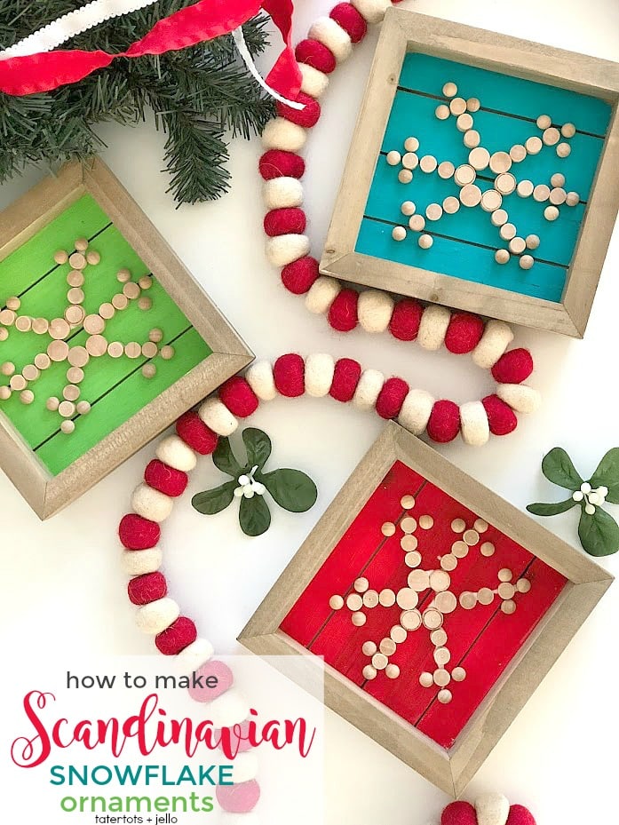 Three framed ornaments with snowflake patterns made from small wooden beads are displayed on green, blue, and red backgrounds. A red and white felt garland and sprigs of faux greenery complete these charming Christmas tree crafts.