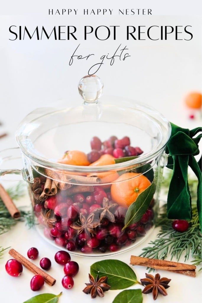 A clear glass pot filled with cranberries, oranges, cinnamon sticks, and star anise, surrounded by pine branches and spices—perfect for simmer pot recipes for gifts. The lid features a green velvet ribbon. Text above: "Simmer Pot Recipes for Gifts.