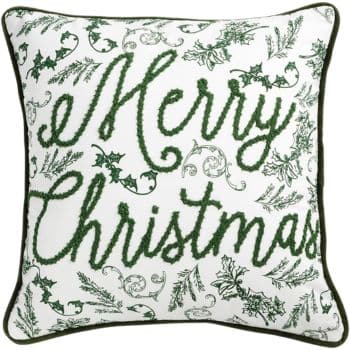 A white throw pillow with green embroidery features the words "Merry Christmas" surrounded by holly leaves and festive foliage. The pillow has green piping along the edges.