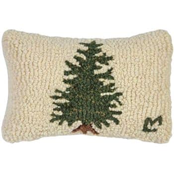 Rectangular cream-colored pillow with a textured, hooked design featuring a green pine tree and a small green leaf in the bottom right corner.