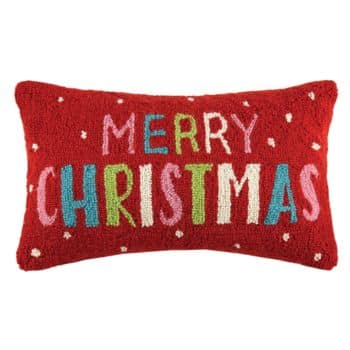 Rectangular red pillow with white dots, featuring the words "Merry Christmas" in colorful, playful letters on the front.