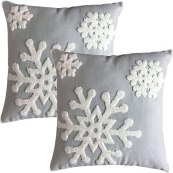 Two light gray square throw pillows with white textured snowflake designs in different sizes on the front.