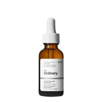 A brown glass dropper bottle of The Ordinary serum with a white label and white cap, standing upright on a plain white background.
