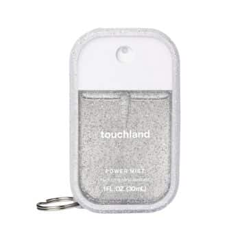 A small, rectangular Touchland Power Mist hand sanitizer with a white top, clear body filled with glittery liquid, and a keychain attachment on the left side.