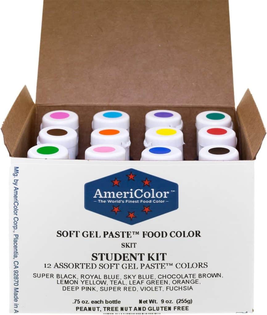 An open box labeled "AmeriColor Soft Gel Paste Food Color Student Kit" contains 12 bottles of assorted food coloring, perfect for adding vibrant shades to your favorite Molded Cookies Recipe, each cap showing a different color inside.