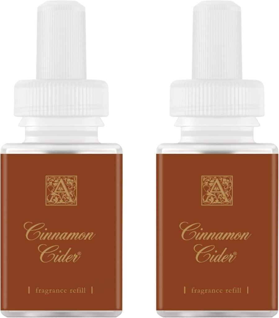 Two brown fragrance refill bottles labeled "Cinnamon Cider" with white caps are placed side by side. White and gold text is printed on the front of each bottle, making them perfect for my favorite Christmas decor displays.