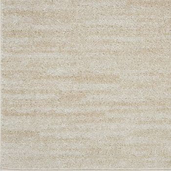 Close-up of a textured beige rug with subtle, uneven horizontal patterns in varying shades of cream and light tan. The material appears soft, creating a cozy and neutral background.