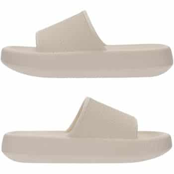 A pair of beige slide sandals with thick, textured soles and wide, ribbed straps shown in a side view on a white background.