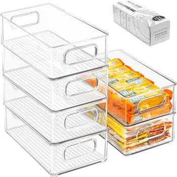 Four clear plastic storage bins are stacked, with an additional bin beside them holding packaged snacks. A box labeled "plastic wrap" is positioned in the background.