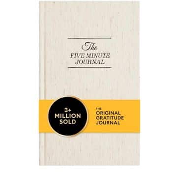 A beige hardcover book titled "The Five Minute Journal" with a yellow band stating "3+ Million Sold" and "The Original Gratitude Journal" across the cover.
