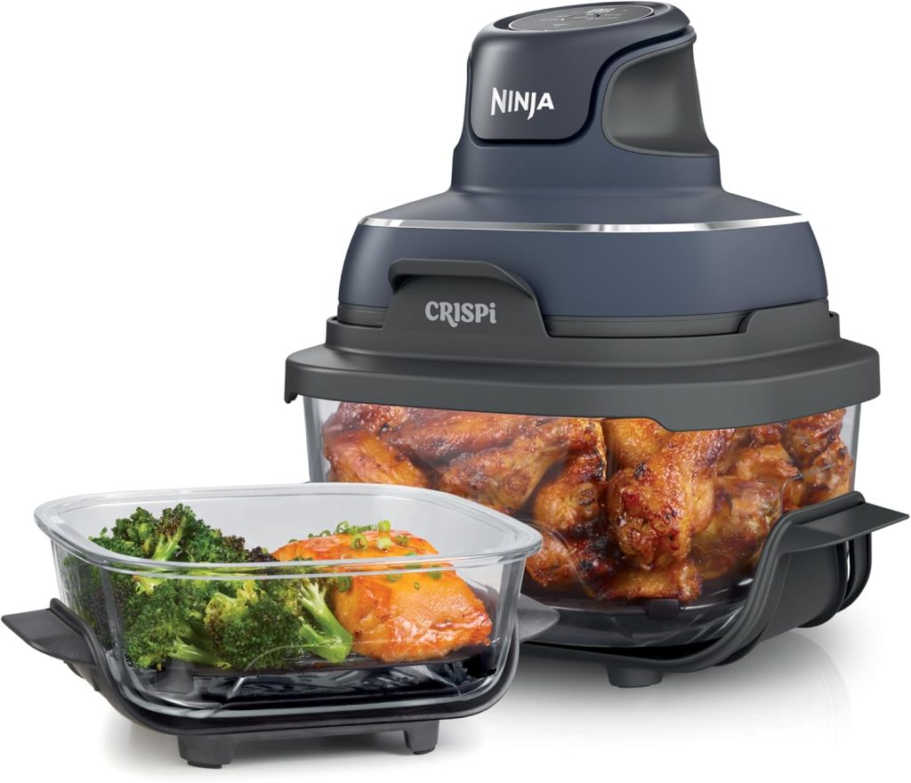 A Ninja CRISPI air fryer filled with cooked chicken wings sits beside a glass container holding cooked broccoli and salmon, perfect for easy dinner ideas.