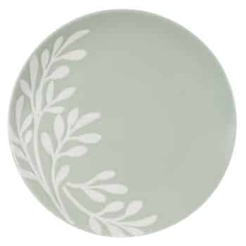 A round, light green plate features a white leafy branch design on one side, creating a simple and elegant pattern.