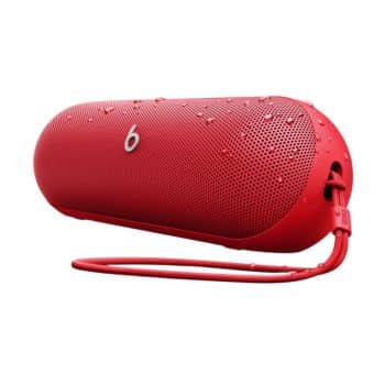 A red portable Beats wireless speaker with water droplets on its surface, featuring a wrist strap and the Beats logo on the front.