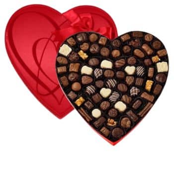 A heart-shaped red box filled with a variety of assorted chocolates, some decorated with white or dark drizzles, opened to display the candies inside.