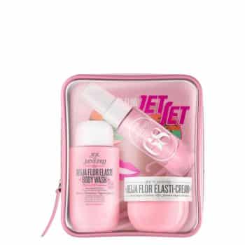 A clear pink zippered pouch contains Sol de Janeiro beauty products, including a body wash, body cream, and spray, all in matching pink packaging, along with a colorful card in the background.