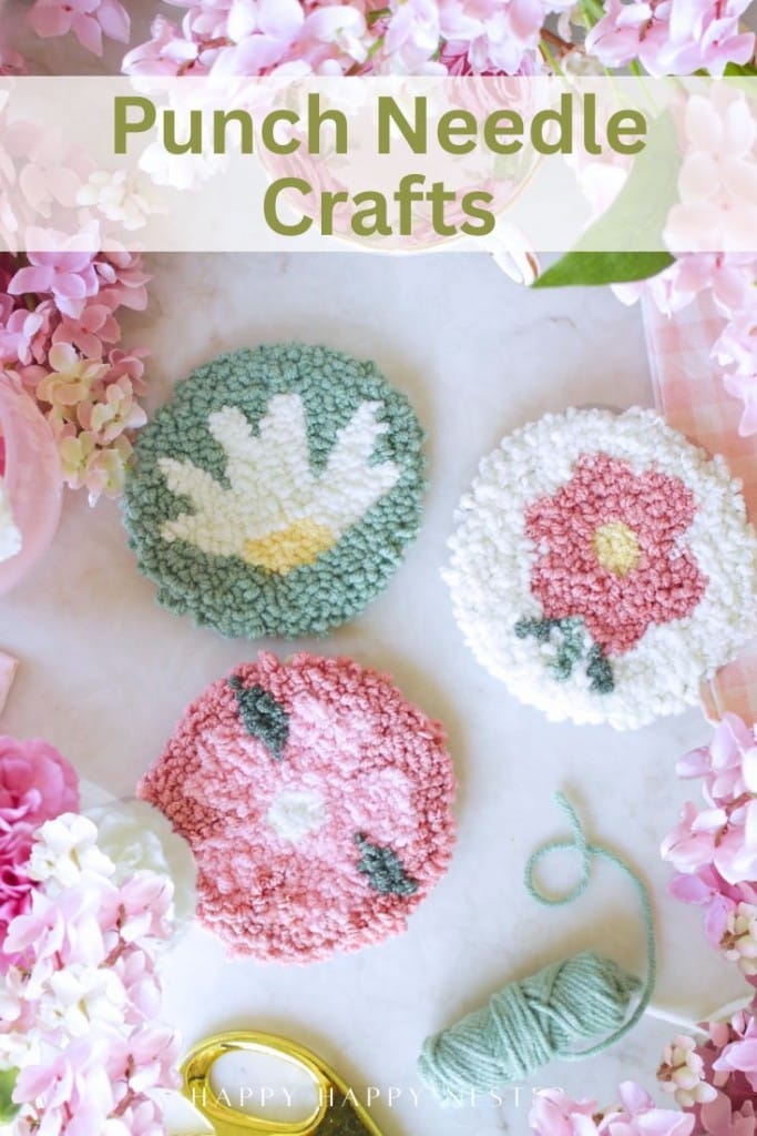 Three round punch needle coasters with floral designs are surrounded by pink flowers, green yarn, gold scissors, and a pink background. The text "Punch Needle Crafts" highlights this charming punch needle crafting DIY scene.
