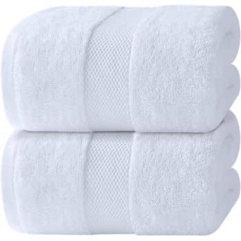 Two white bath towels neatly rolled and stacked on top of each other against a plain background. The towels have a textured band pattern near the edges.