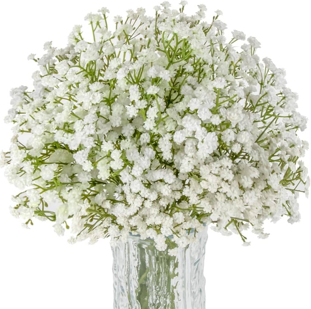 A bouquet of delicate white baby's breath, often found in a spring flower wreath, arranged in a clear, textured glass vase against a white background.