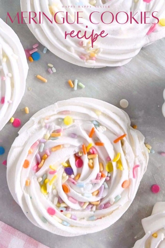 A close-up of a swirled meringue cookie topped with colorful sprinkles on a baking sheet. Other cookies and scattered sprinkles surround it. The text reads: "Meringue Cookies Recipe"—perfect for your next homemade meringue cookies recipe!.