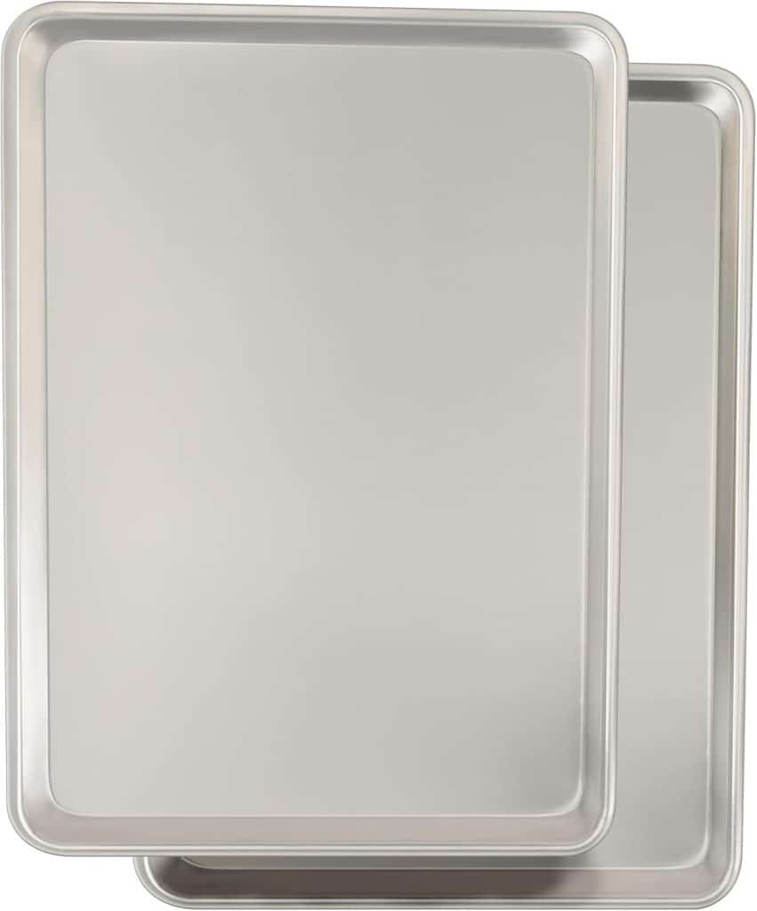 Two overlapping rectangular metal baking sheets with raised edges, perfect for preparing your favorite cherry blossom cookie recipe. The smooth, shiny pans rest on a plain white background and appear clean and unused.