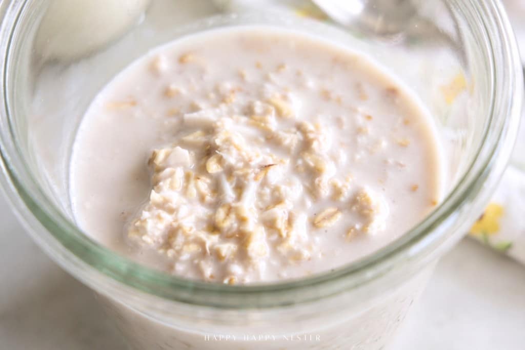 A close-up of an overnight oats recipe with yogurt, soaked in milk and served in a glass jar with a creamy texture.