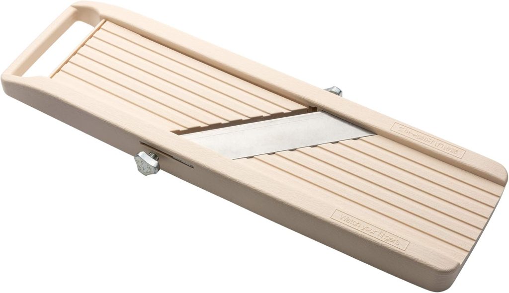 A beige vegetable slicer with a sharp metal blade in the center, a grooved surface, and an integrated handle on one end—perfect for prepping veggies for onion ring pizza.