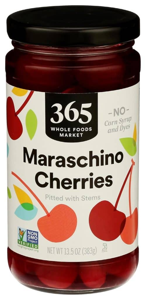 A jar of 365 Whole Foods Market Maraschino Cherries, perfect for your next cherry blossom cookie recipe. Features a white label with red cherry illustrations, “NO corn syrup and dyes” text, and a Non-GMO Project Verified badge. Net weight is 13.5 oz (383g).