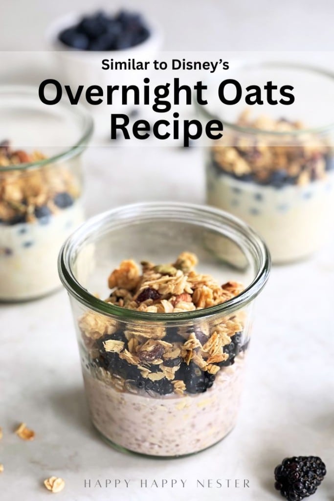Three glass jars filled with overnight oats recipe with yogurt, topped with granola and blueberries. The front jar is in focus, and text above reads, “Similar to Disney’s Overnight Oats Recipe.”.