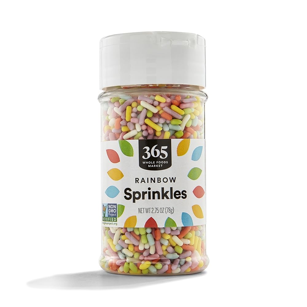 A clear plastic container of 365 Whole Foods Market Rainbow Sprinkles, perfect for topping a cherry blossom cookie recipe. The label displays the brand, product name, and Non-GMO Project Verified logo.