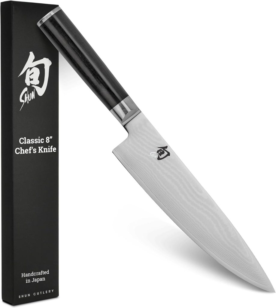 A Shun Classic 8-inch chef's knife with a black handle is shown next to its black box packaging, featuring Japanese kanji and branding—perfect for expertly slicing ingredients for dishes like onion ring pizza.
