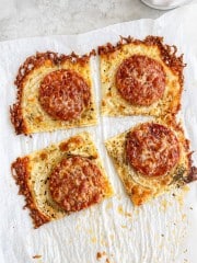 Four square slices of crispy cheese bread topped with pepperoni and grated cheese, arranged on parchment paper with browned, bubbly edges—perfect as a savory side for your favorite onion ring pizza recipe.