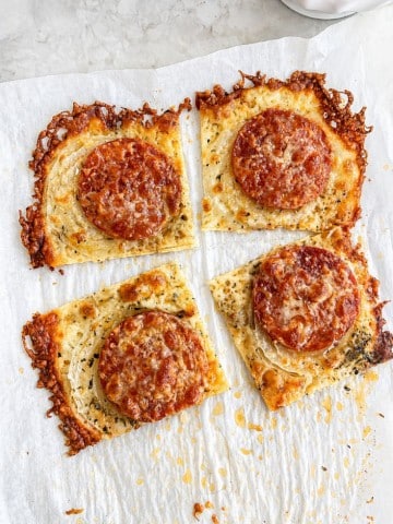 Four square slices of crispy cheese bread topped with pepperoni and grated cheese, arranged on parchment paper with browned, bubbly edges&mdash;perfect as a savory side for your favorite onion ring pizza recipe.