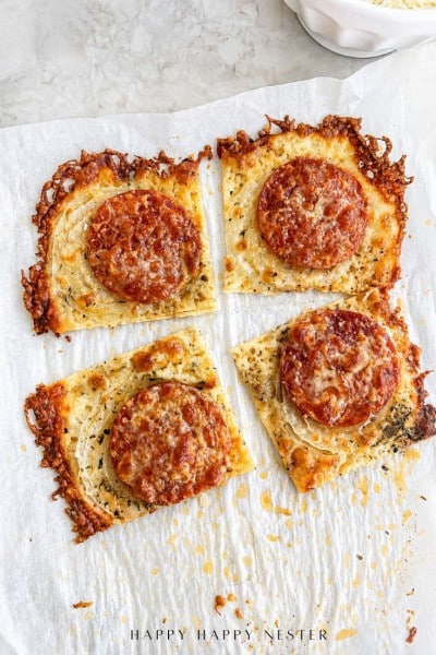 Four square slices of crispy cheese bread topped with pepperoni and grated cheese, arranged on parchment paper with browned, bubbly edges—perfect as a savory side for your favorite onion ring pizza recipe.