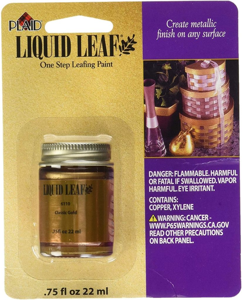 A package of Plaid Liquid Leaf One Step Leafing Paint in Classic Gold, 0.75 fl oz (22 mL). Perfect for projects like an oyster shell wreath DIY, the package features safety warnings and a gold-painted vase and basket in the background.