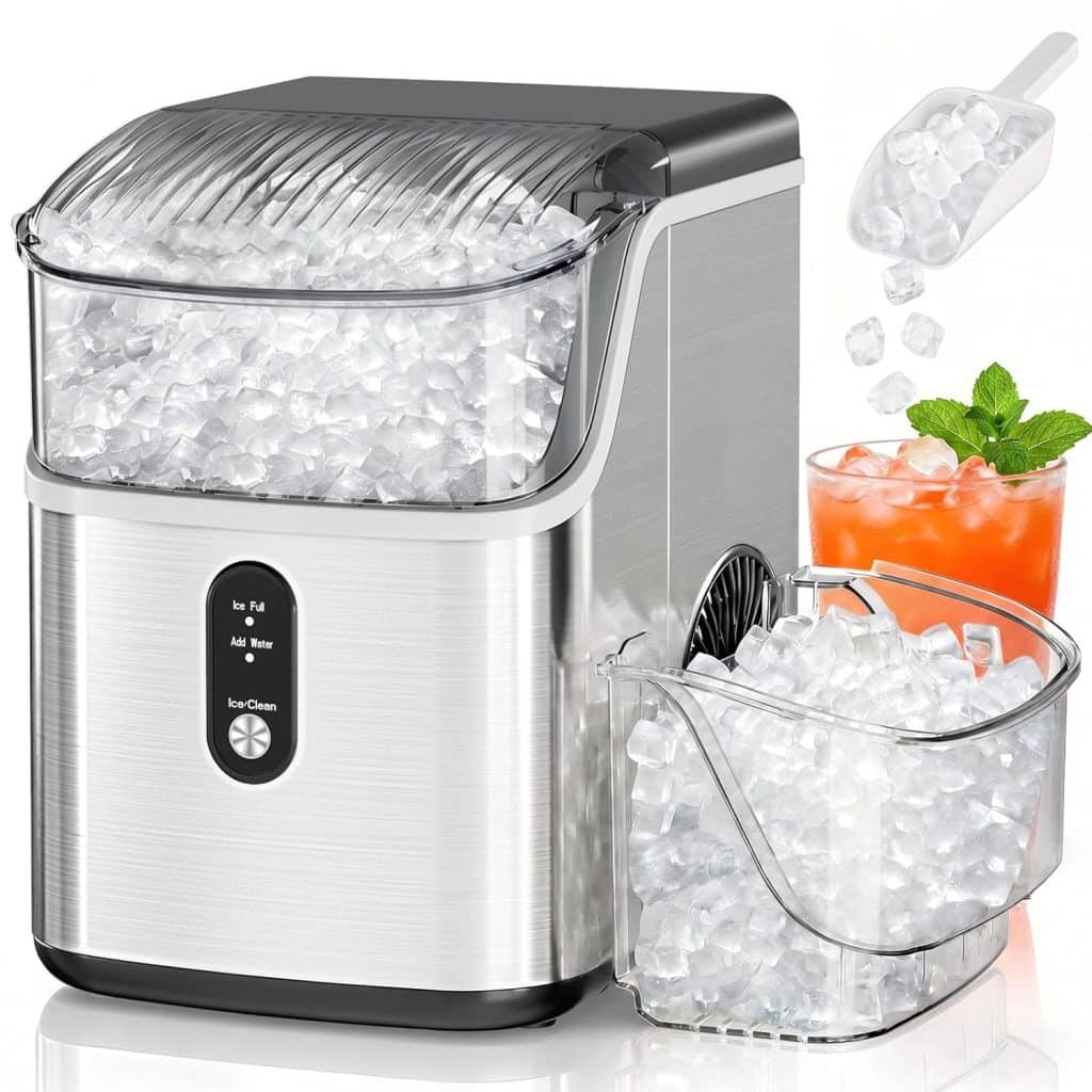 A countertop ice maker filled with ice cubes, a removable ice basket nearby, a plastic scoop pouring ice, and a glass of ginger beer mocktail recipe with mint and orange garnish beside the machine.