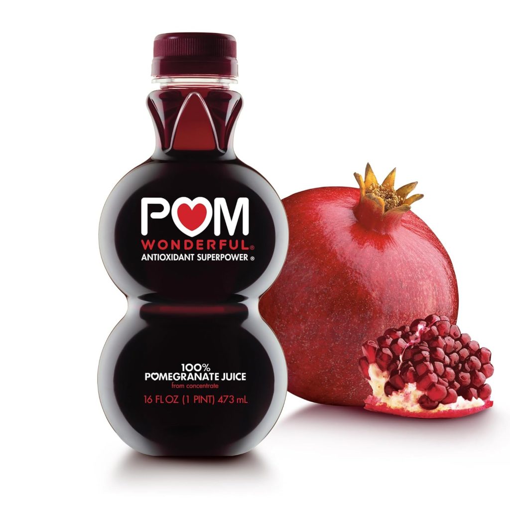 A bottle of POM Wonderful 100% pomegranate juice stands next to a whole and a sectioned pomegranate with exposed seeds on a white background—perfect for your next ginger beer mocktail recipe.