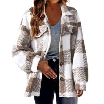 A woman wearing a gray top, black pants, and a cozy white and beige plaid button-up sherpa jacket poses with one hand on her hip.