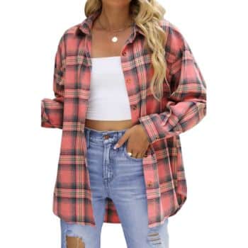 Woman wearing a pink and black plaid shirt over a white crop top and ripped light blue jeans, posing with one hand in her pocket.
