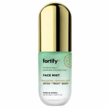 A bottle of Fortify+ Face Mist with a gold cap, labeled as hydrating and barrier-protecting, containing niacinamide and hyaluronic acid. The bottle is mint green and white, and made in Korea.