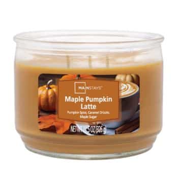 A jar candle labeled “Maple Pumpkin Latte” with pumpkin spice, caramel drizzle, and maple sugar scents. The label shows pumpkins, autumn leaves, and a latte. The candle is orange-brown.