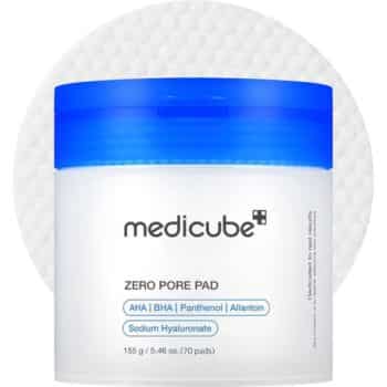 A container of Medicube Zero Pore Pad with a blue lid is shown in front of a white textured pad. The label lists ingredients like AHA, BHA, Panthenol, Allantoin, and Sodium Hyaluronate.